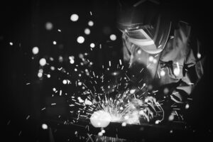 Employee welding steel with sparks using mig mag welder - focus